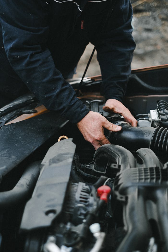 Close-up of a mechanics hands working on a car engine inside a workshop.